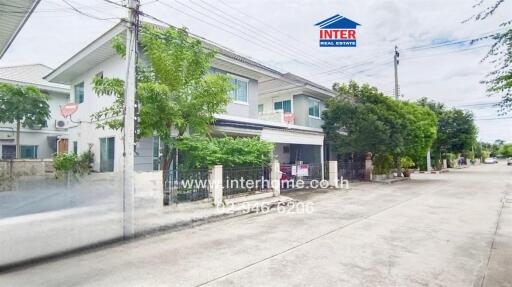 Two-story residential building with driveway and trees