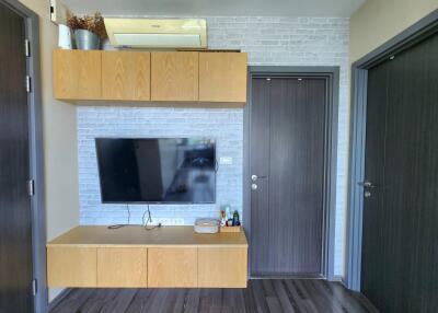 Living room with mounted TV, wooden cabinets, and modern doors