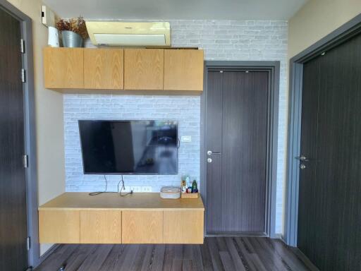 Living room with mounted TV, wooden cabinets, and modern doors