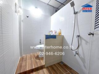 Modern bathroom with half-wall, shower area, and wooden floor tiles