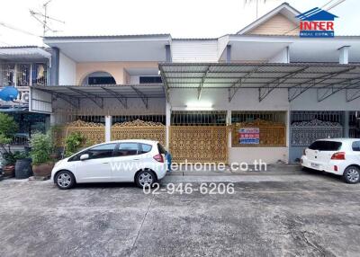 Front view of a residential building with two parked cars and a covered area