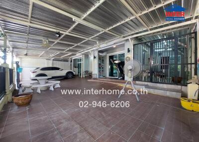 Covered garage area with parked car and outdoor furniture