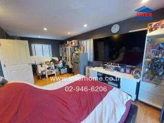 Bedroom with a large TV, bed, and storage shelves