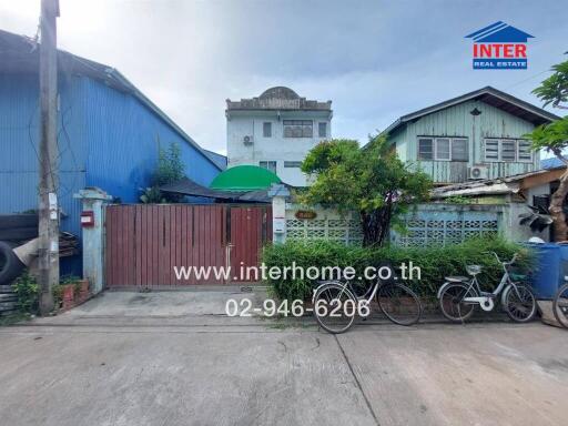 Front view of residential buildings and entrance gate with bicycles and greenery