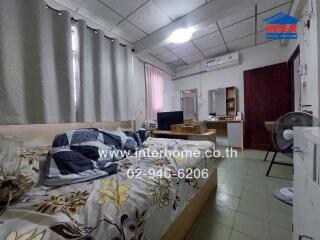 Cozy bedroom with patterned bedspread, window drapes, and various furnishings