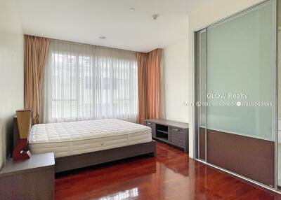 Spacious bedroom with wooden floor, large bed, bedside table, storage unit, and a sliding wardrobe