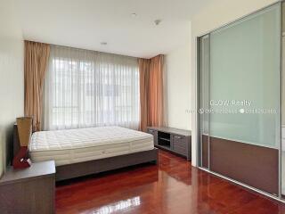 Spacious bedroom with wooden floor, large bed, bedside table, storage unit, and a sliding wardrobe