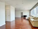 Spacious living room with large windows, sofa, and hardwood floor