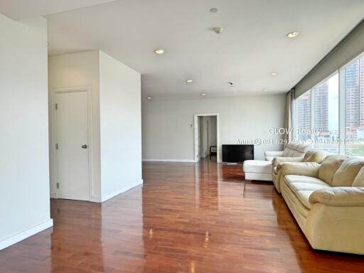 Spacious living room with large windows, sofa, and hardwood floor