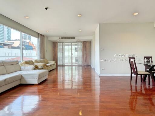 Spacious living room with wooden flooring, large windows, and contemporary furniture