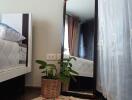 Bedroom corner with a mirror, plant, and rug