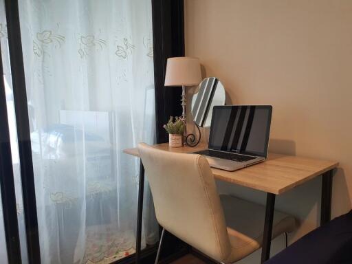 Bedroom with a study desk, chair, lamp, and laptop near a window with white curtains