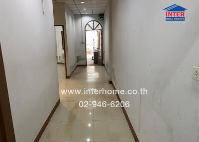 Corridor in building with a view of an arched door and tiled flooring