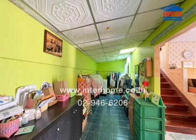 A corridor with vibrant green walls, storage cabinets, ceiling tile design, and a staircase leading to an upper floor.