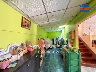 A corridor with vibrant green walls, storage cabinets, ceiling tile design, and a staircase leading to an upper floor.