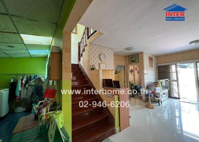 Interior view of a house with a staircase, living area, and laundry corner