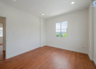 Bright and spacious empty bedroom with wooden floors and a window.