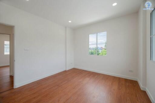 Bright and spacious empty bedroom with wooden floors and a window.