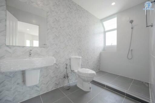 Bright modern bathroom with a toilet, sink, and shower area.