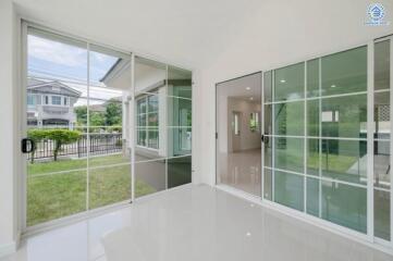 Spacious living area with large glass doors opening to a green lawn