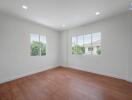 empty room with wooden flooring and large windows