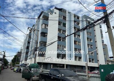 Low-rise residential building exterior with multiple floors and parked cars