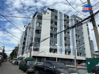 Low-rise residential building exterior with multiple floors and parked cars