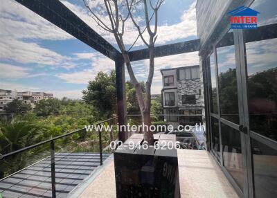 Spacious balcony with a tree and glass railing, offering scenic views