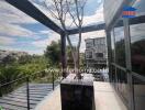 Spacious balcony with a tree and glass railing, offering scenic views