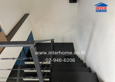 Indoor staircase with black steps and metallic railing