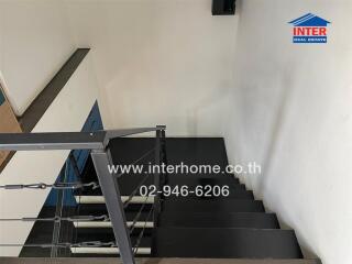 Indoor staircase with black steps and metallic railing