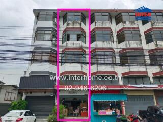 Exterior view of multi-story residential building with ground floor storefront