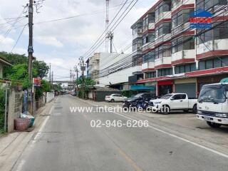 Street view of a residential area with buildings and parked vehicles