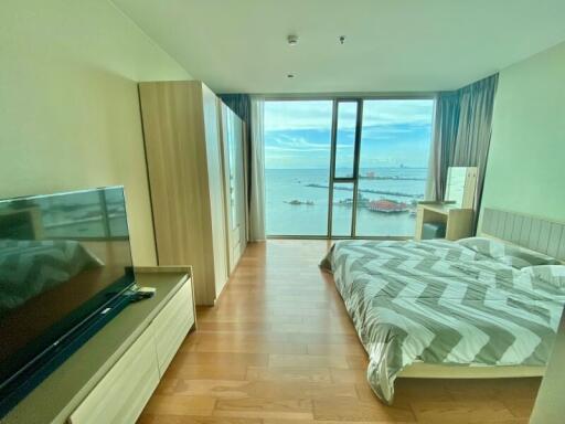 Spacious bedroom with sea view, TV, wooden flooring and modern decor