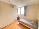 Minimalistic bedroom with wooden flooring, a bed, window with curtains, and an air conditioner