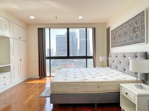 Bright bedroom with large windows offering a city view and featuring built-in closets.