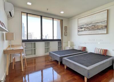 Bedroom with two beds, large window, and study desk