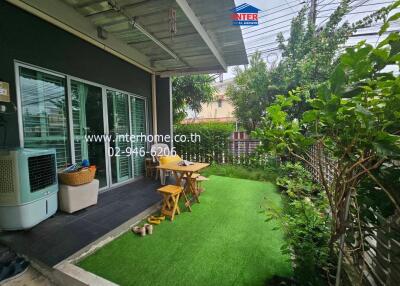 A cozy backyard with a small seating area and artificial grass