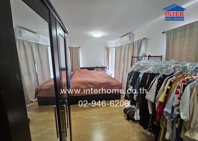 Spacious bedroom with a large bed, wardrobes, and clothing racks