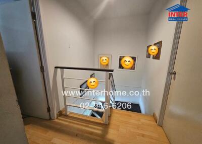 Staircase landing area with wall decorations and wooden flooring