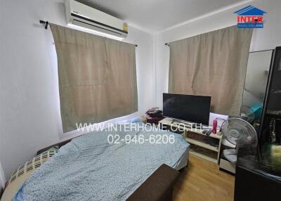 Bedroom with bed, television, air conditioner, and window curtains