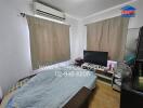 Bedroom with bed, television, air conditioner, and window curtains