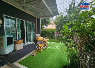 covered patio area with artificial grass, seating, and garden