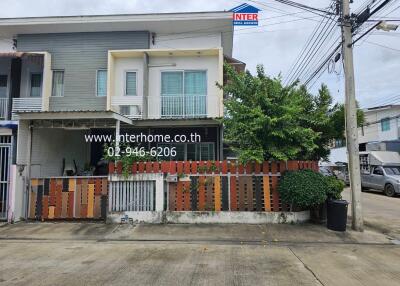 Exterior view of a two-story house with a colorful front fence