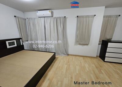 Master bedroom with wooden flooring and neutral curtains