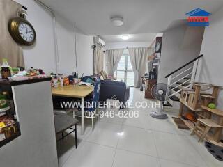 Spacious living area with dining table, staircase, and large window