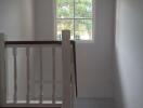 Bright staircase area with wooden handrail and large window