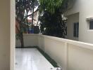 A view of a clean and tiled outdoor space with a tree and neighboring buildings