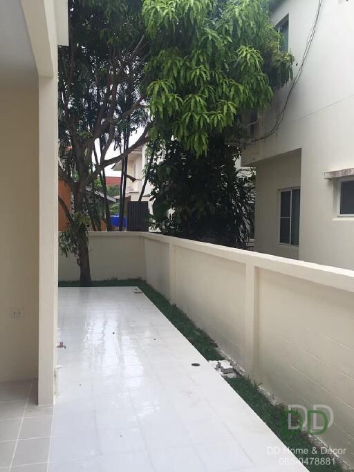 A view of a clean and tiled outdoor space with a tree and neighboring buildings