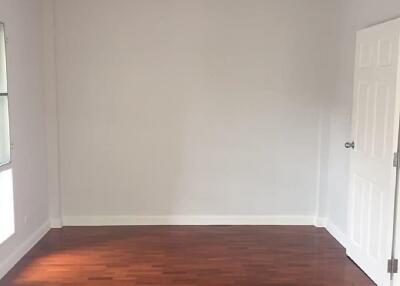 Empty room with hardwood flooring and a door